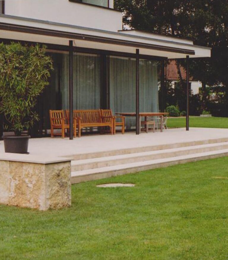 Terasse und Treppe aus Stein vor einem Garten